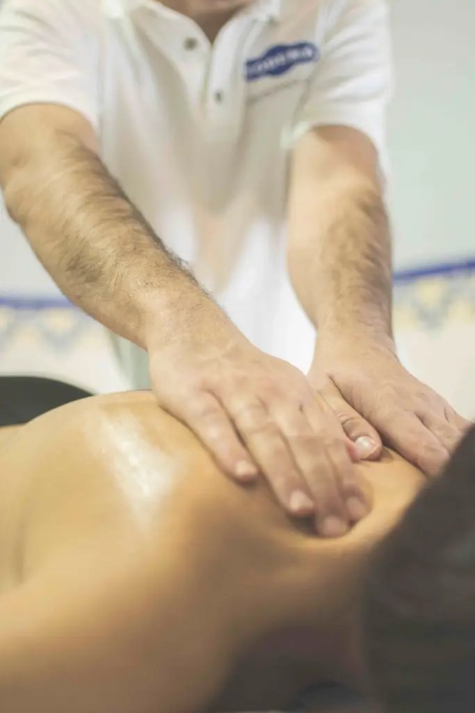 Rafael Nunes, de camisa polo branca, massageando as costas de um cliente
